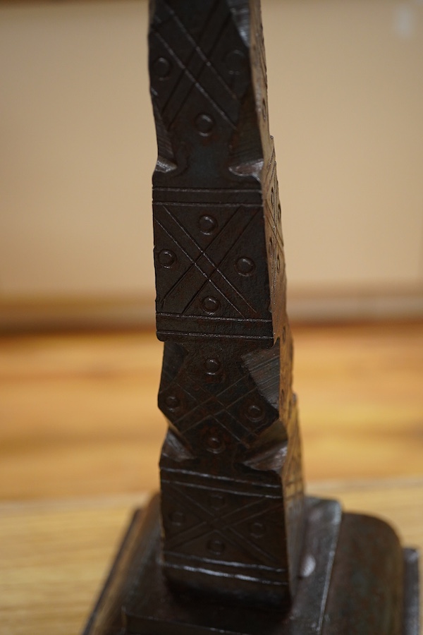An iron candle stick with incised geometric decoration, 49cm high